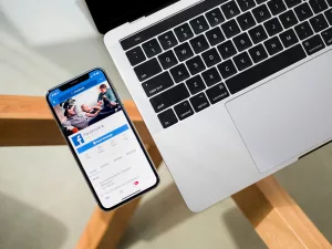 facebook app showing on iphone beside the laptop