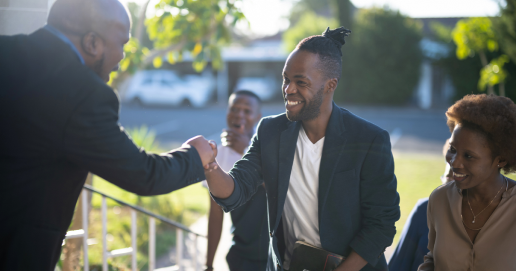 Smiling young man shaking another man's hand