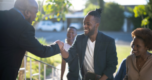 Smiling young man shaking another man's hand