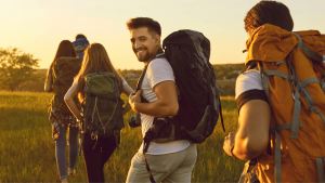 Man smiling as he hikes with friends with backpacks on