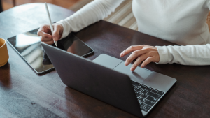 woman's hand using the laptop and holding an apple pencil