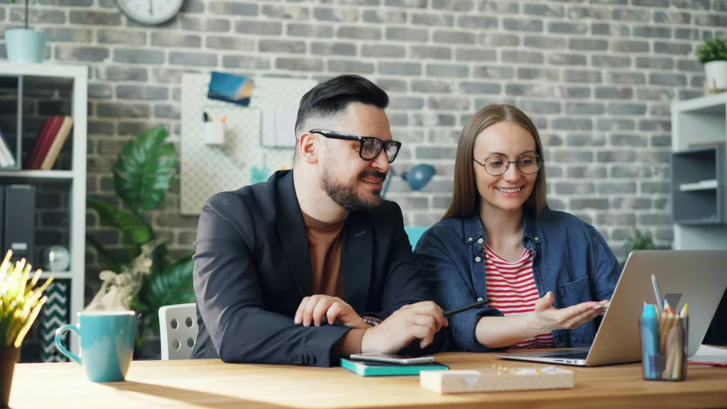 man and woman in glasses looking or working on the laptop