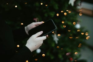 Person holding a phone with Christmas lights in the background
