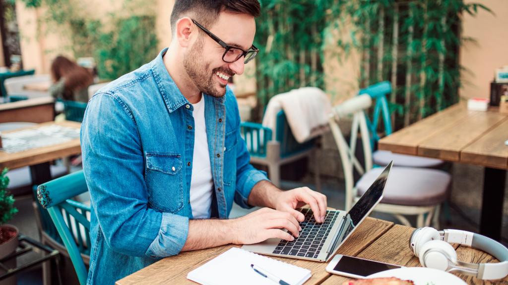 man smiling while typing on laptop
