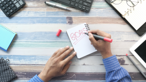 Man Writing New Year Goals on Notepad