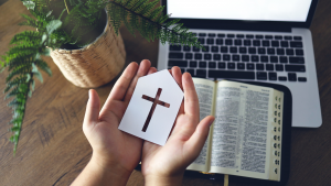hand with cross sign in front of laptop